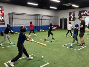 Hitclub indoor baseball training scene with athletes practicing and coaches guiding.