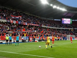 7m live soccer match atmosphere with fans cheering, players in action, vibrant stadium lights.